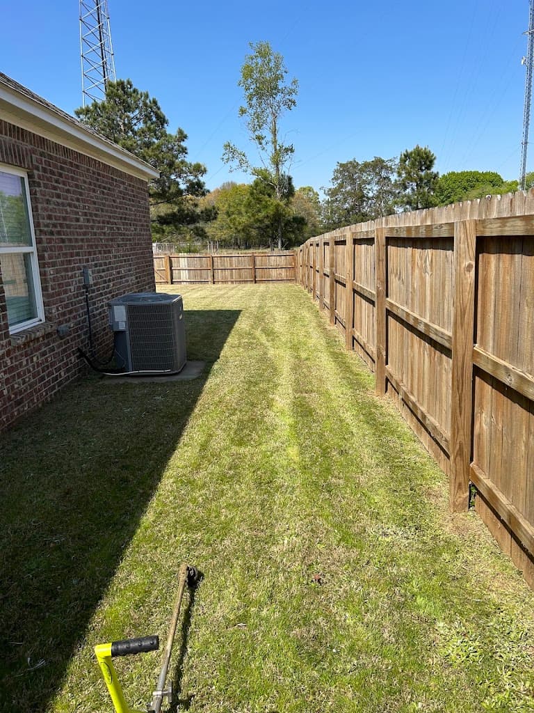Crisp mowed stripes along a wooden privacy fence
